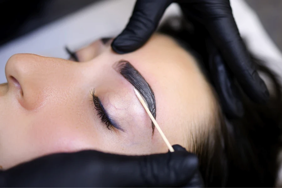 Mujer recibiendo extensiones de cejas por una esteticista