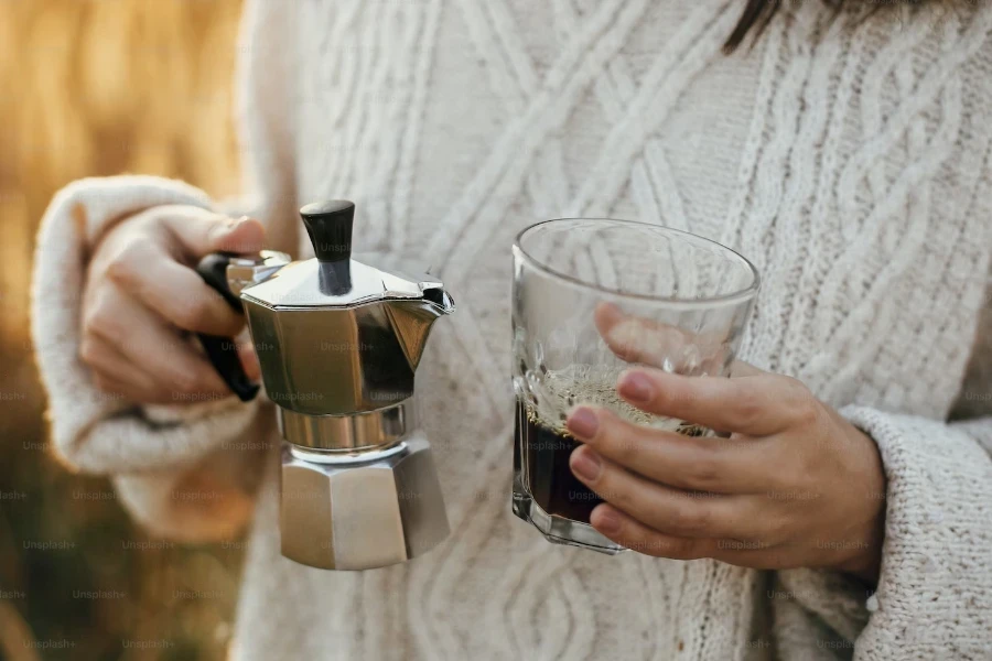 Woman holding a one-cup moka pot and glass