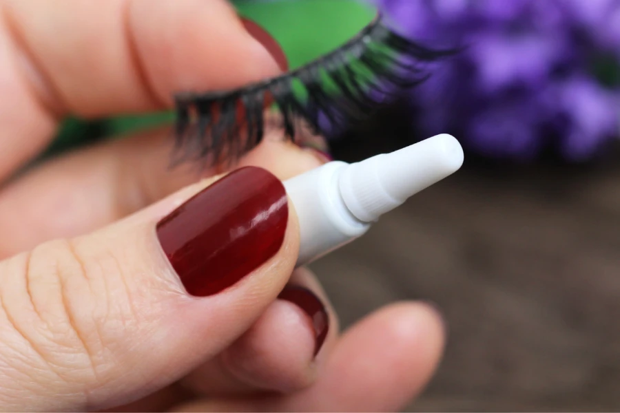 Woman holding eyelash glue and extension