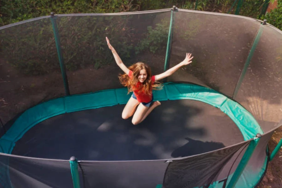 Woman jumping on oval trampoline with netting around it