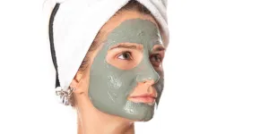 Mulher olhando de lado com uma máscara facial de argila