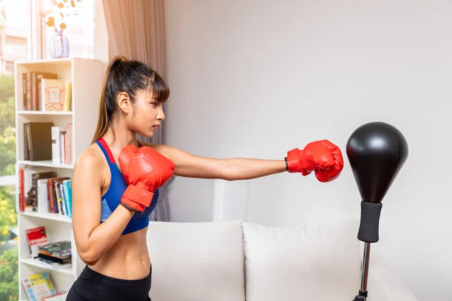 Mujer golpeando un saco de boxeo independiente con guantes de boxeo rojos