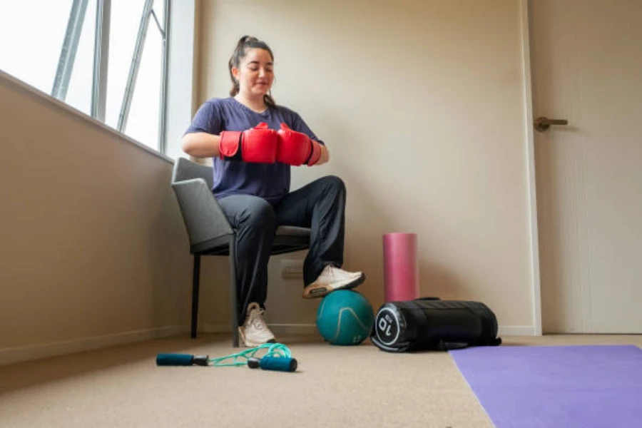 Woman sitting on chair wearing red boxing gloves