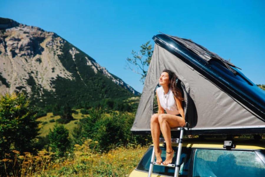 Woman sitting on the edge of pop-up rooftop tent