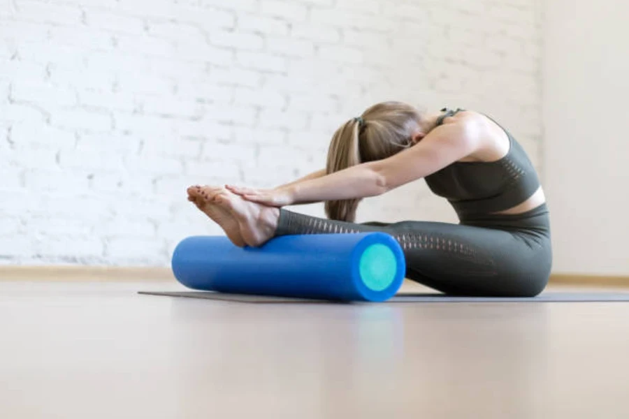 Woman using blue foam roller to stretch calves