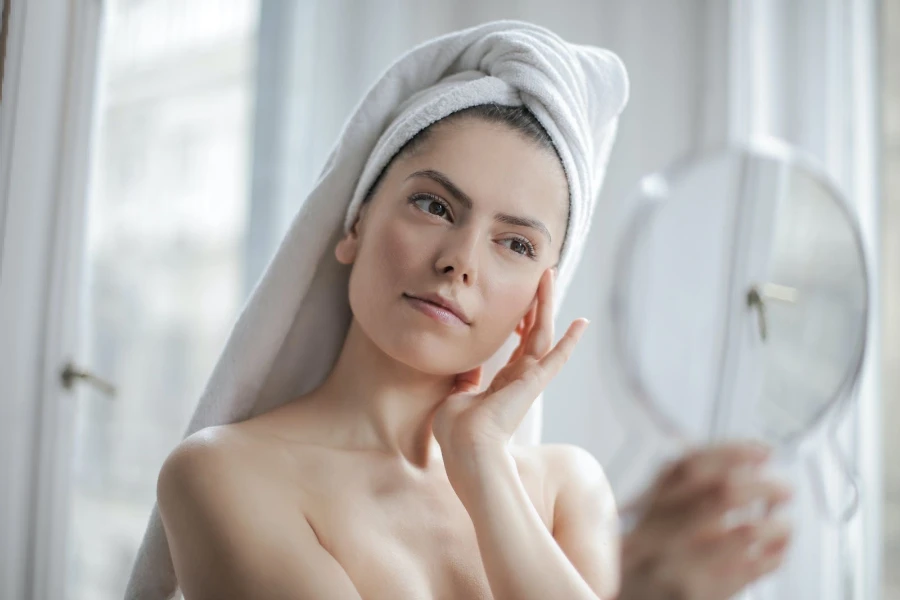 Woman with a head towel looking at a mirror