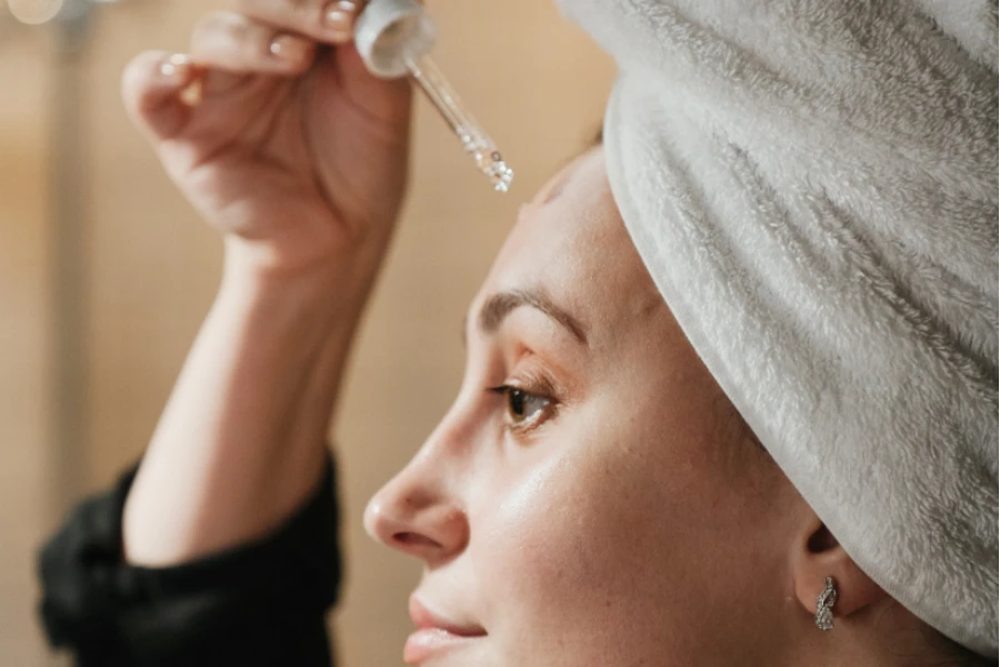 Woman with a towel using a face serum