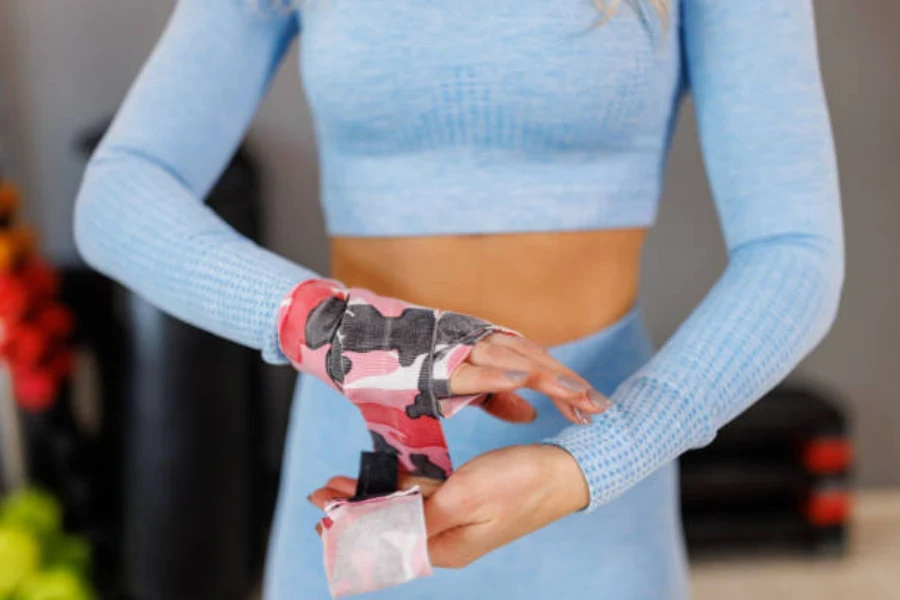 Woman wrapping wrists in pink and black hand wrap