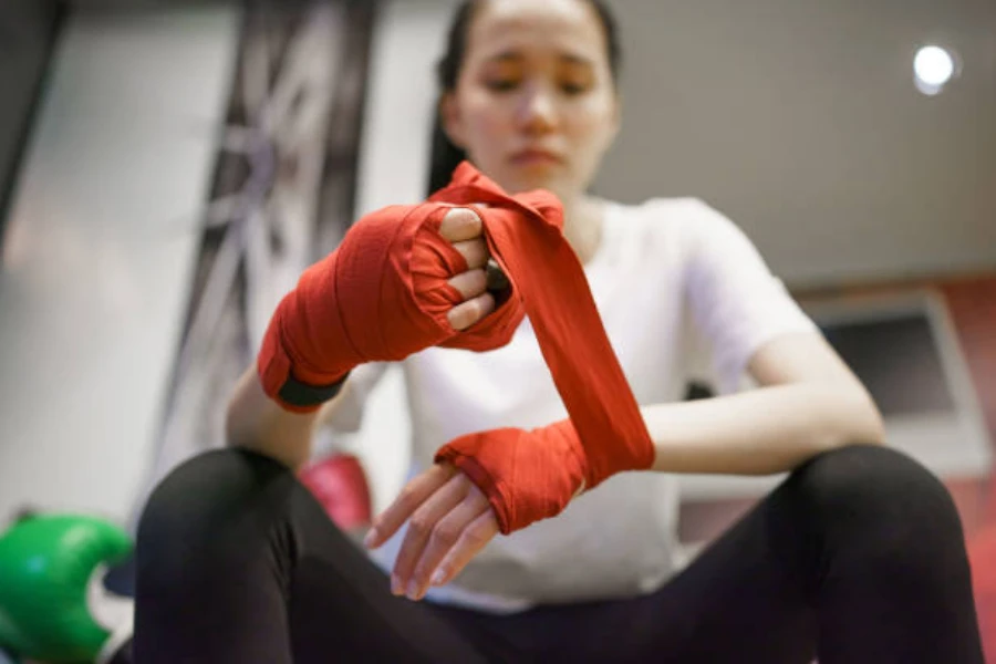 Mulher envolvendo os pulsos em envoltório vermelho para boxe