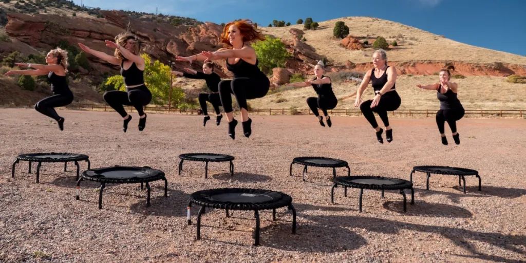 Donne in un ambiente desertico che saltano su trampolini neri per esercizi