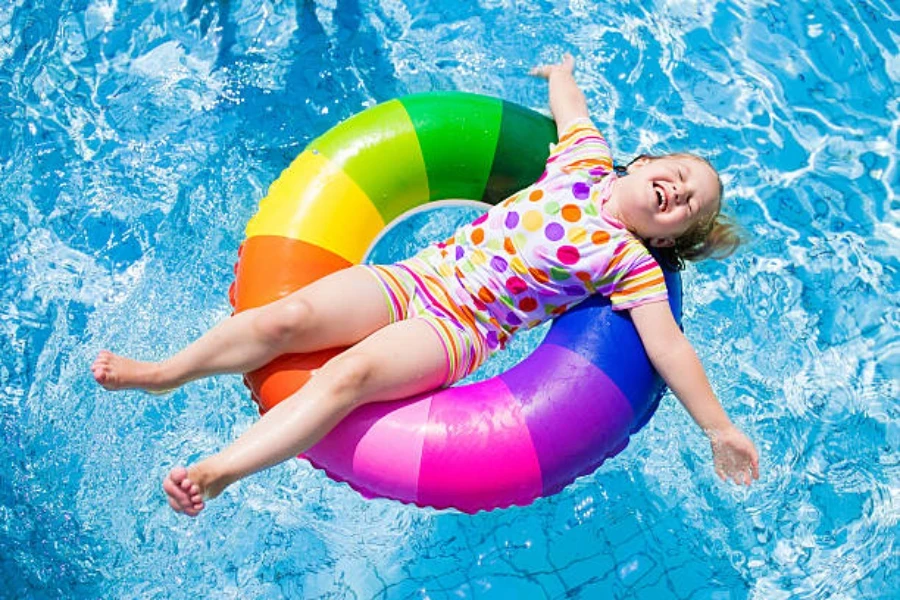 Niña acostada sobre un anillo de donut inflable multicolor