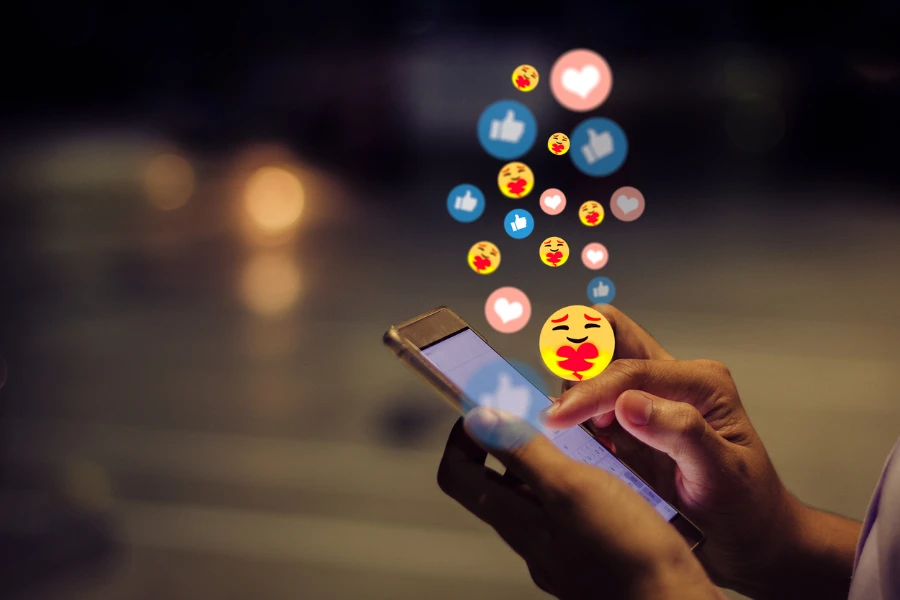 Mujer joven usando un teléfono inteligente con íconos emoji