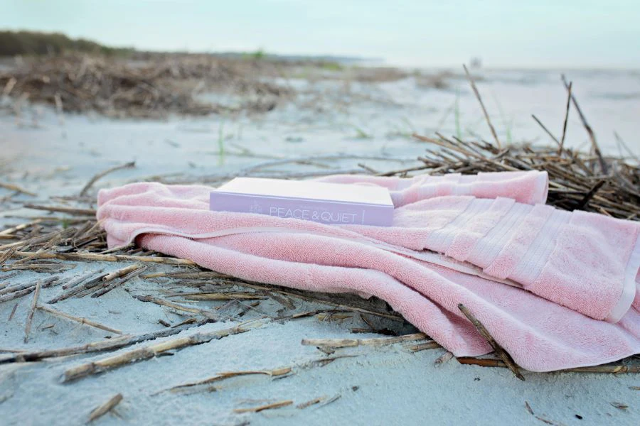 كتاب على منشفة الشاطئ الوردية