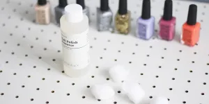 A bottle of nail polish remover next to nail polishes