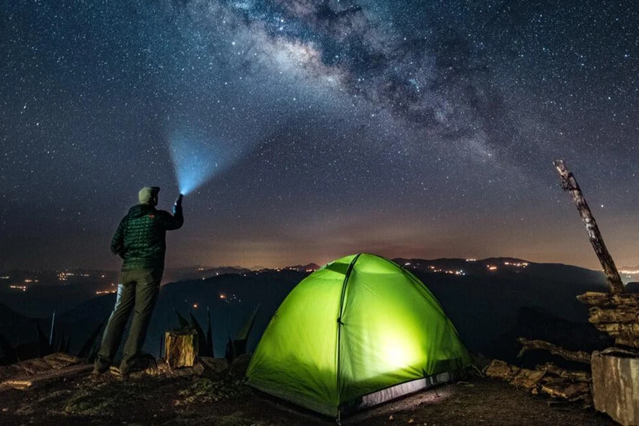 A camper pointing a flashlight to the sky