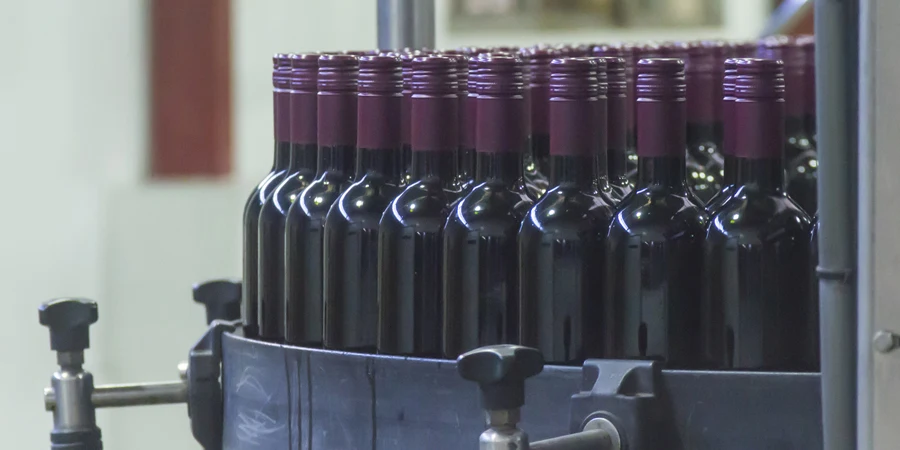 A group of red chilean glass bottles in automatic bottling process in a wine factory