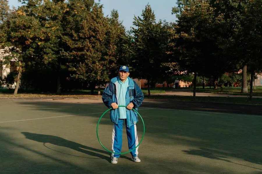 A man in a blue and white polyester tracksuit holding a hula hoop