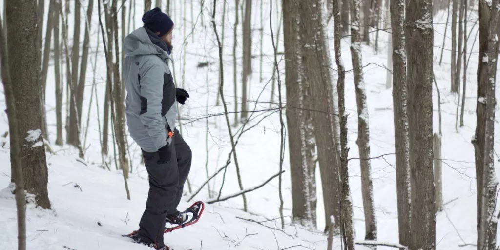 Seorang pria bermain sepatu salju di hutan