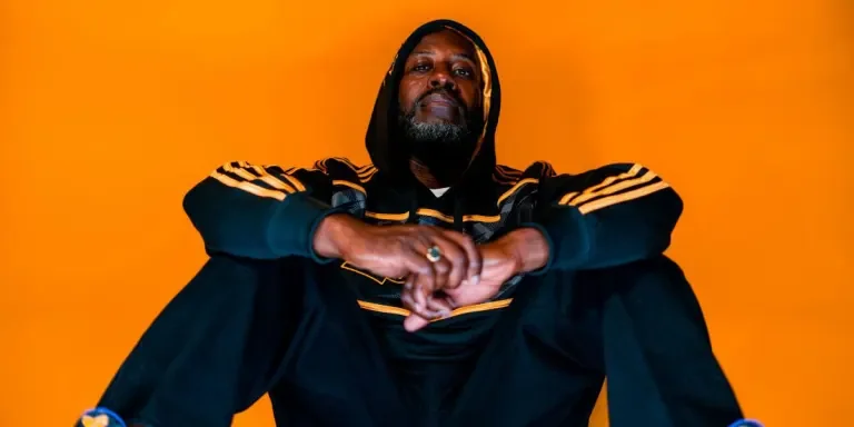 A man wearing a black and yellow striped two piece tracksuit
