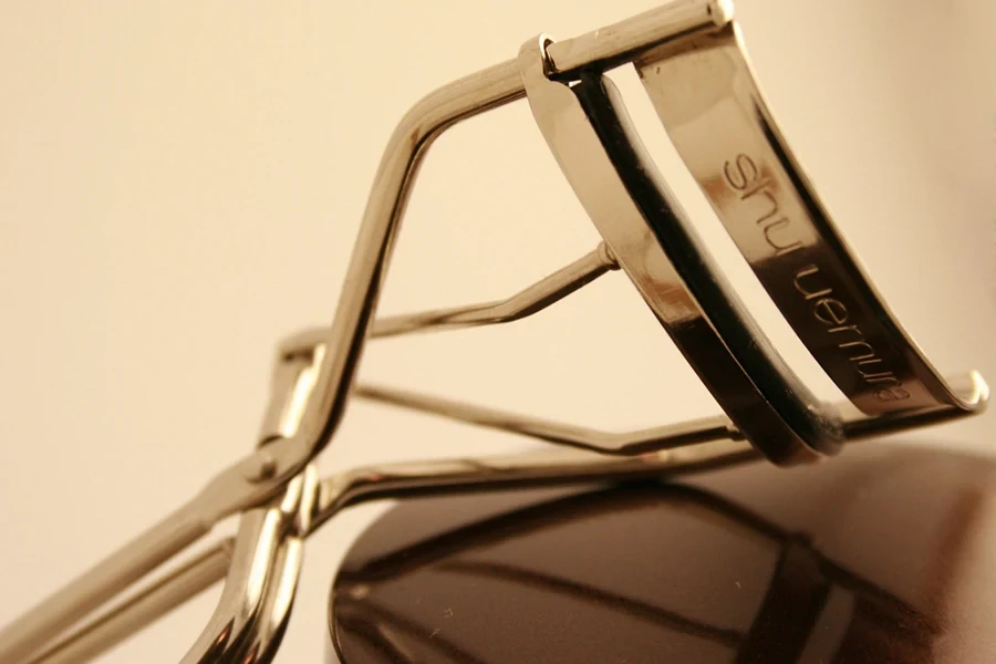 A metal eyelash curler on a colored background