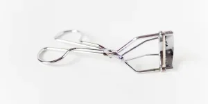 A metal eyelash curler on a white background