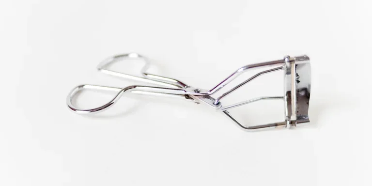 A metal eyelash curler on a white background