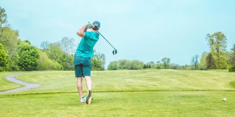 A player swinging his golf club after taking a shot