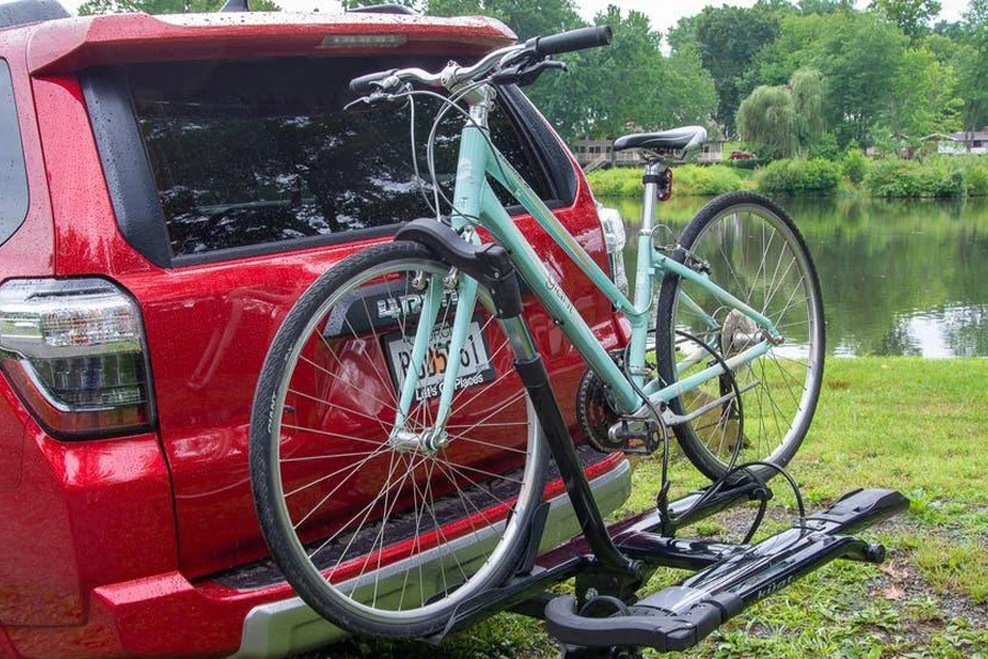 A red car with a bicycle kept on hitch rack