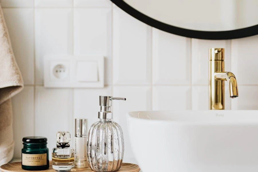 A vessel sink with golden tap and skincare products