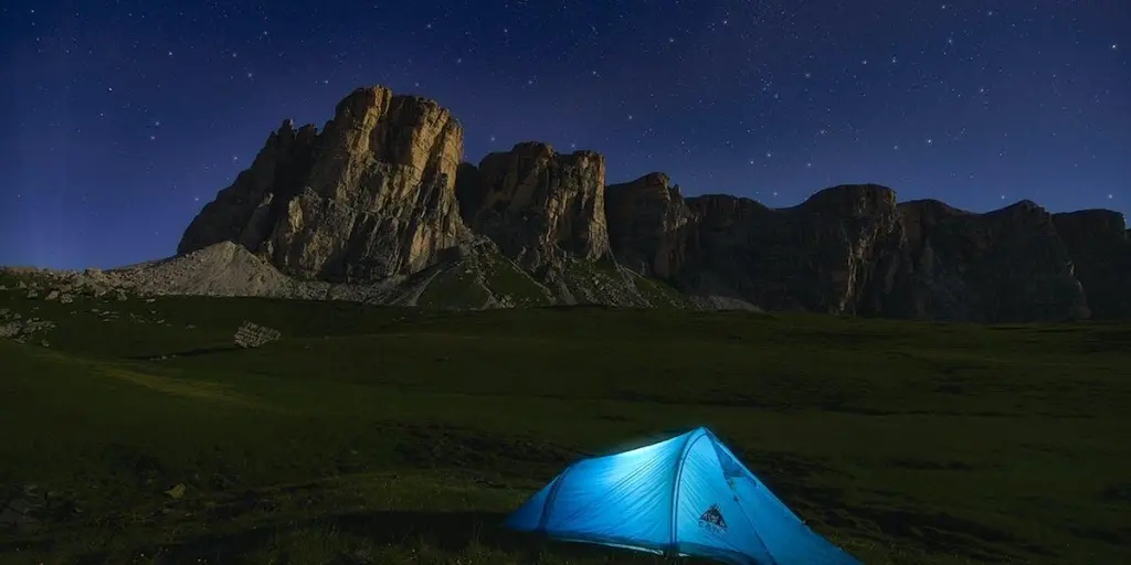 Ein beleuchtetes blaues Zelt in einem Tal