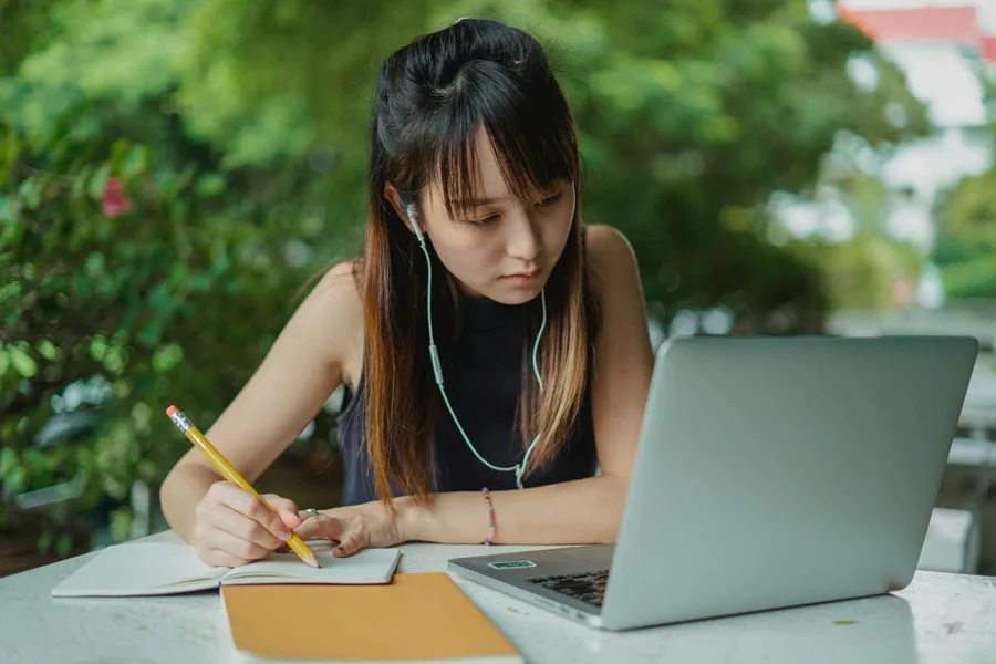 Asyalı kadın kablolu kulaklıkla video dersi izliyor