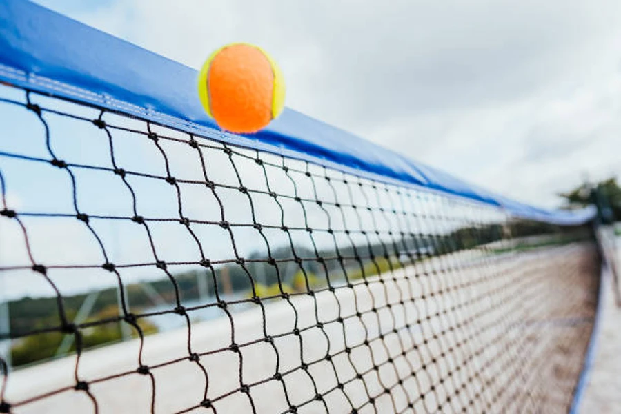Beach tennis ball hitting the top of the net