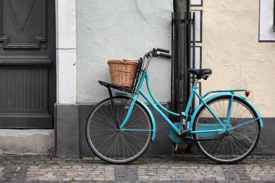 Bicicleta azul con cesta de mimbre unida al manillar.