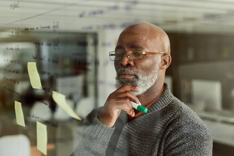 Businessman brainstorming ideas with notes on a glass wall