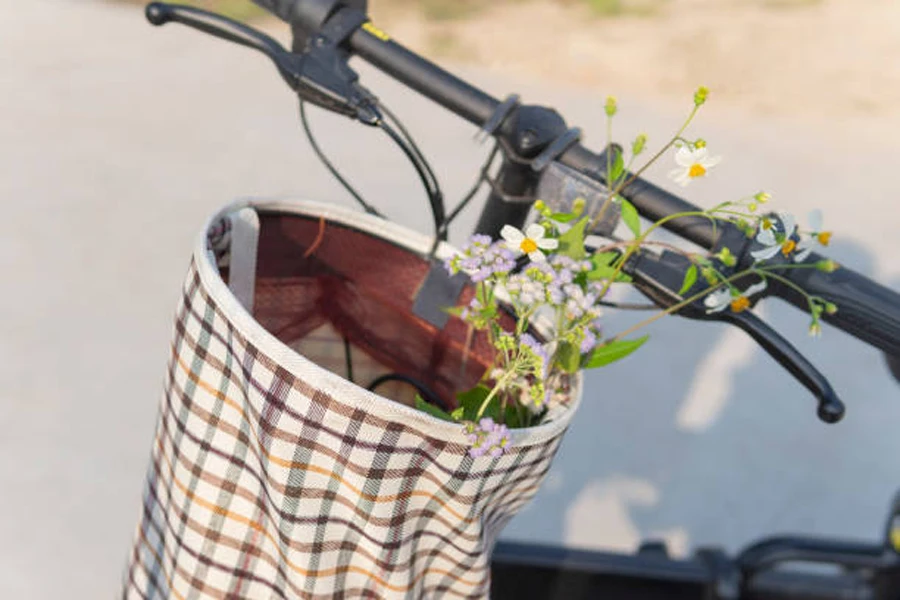 Холщовая велосипедная корзина с цветами внутри.