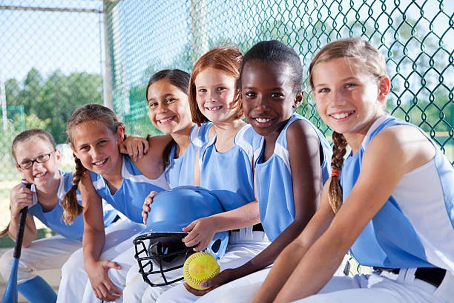 Children sitting on bench wearing matching softball jerseys