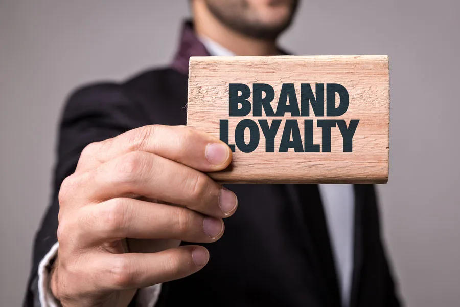Close-up photo of a man holding a “BRAND LOYALTY sign