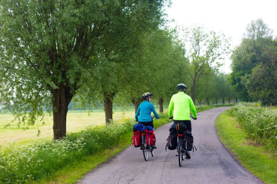 Pareja en bicicleta por un sendero arbolado con alforjas