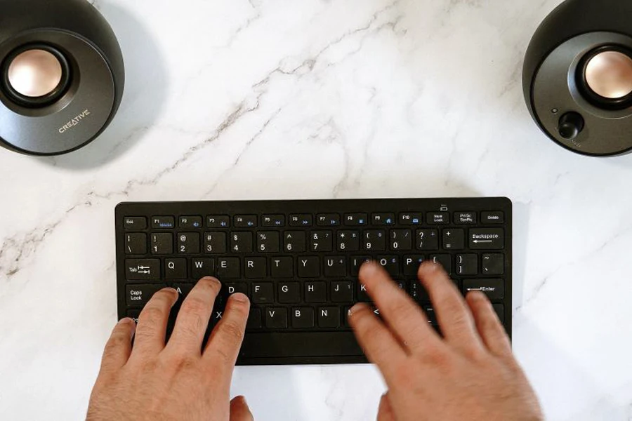 創造的な Pebble スピーカーと白いテーブル上のキーボード