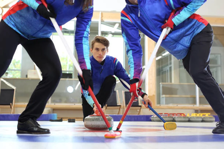 Curling team wearing curling gloves while sweeping ice