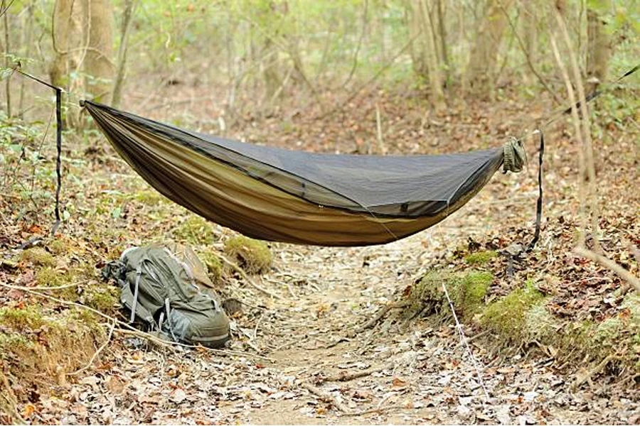 Tempat tidur gantung berwarna hijau tua dengan kelambu hitam di atasnya