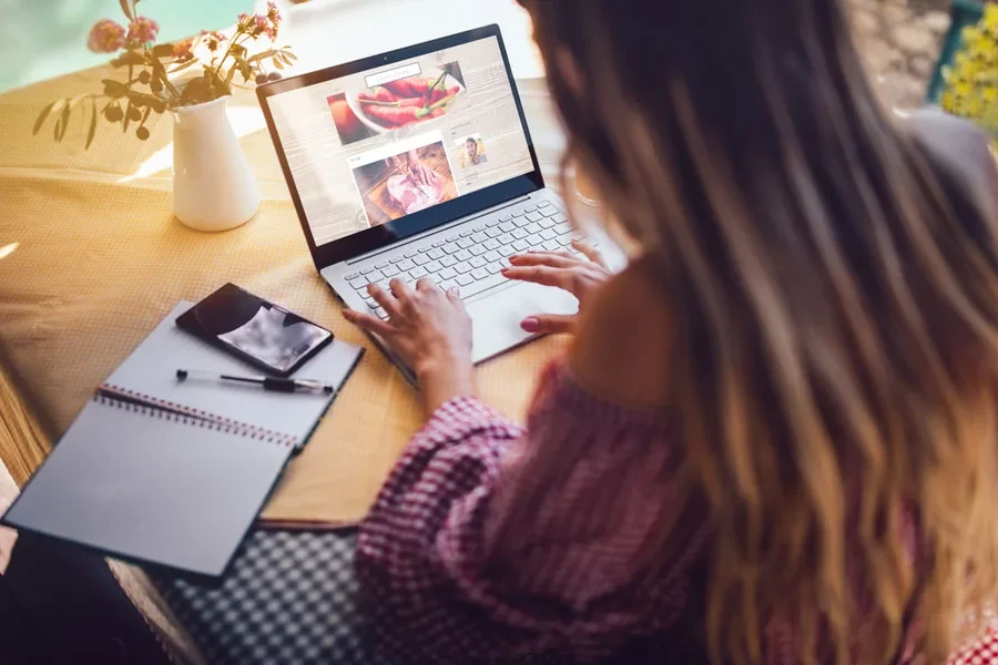 Female food blogger using her laptop at home