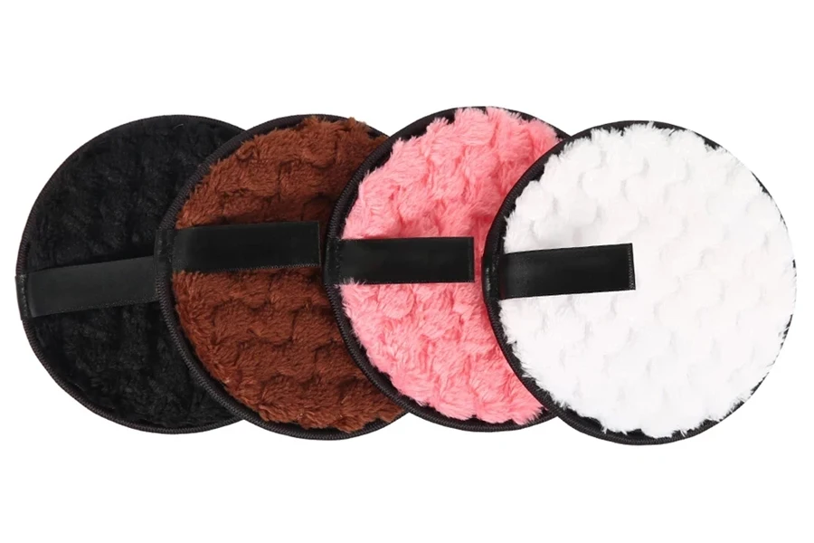 Quatro puffs cosméticos redondos com cores diferentes dispostos ordenadamente