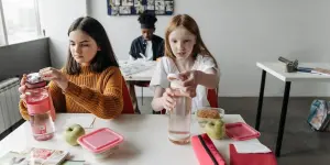 Девочки открывают бутылки с водой во время обеда