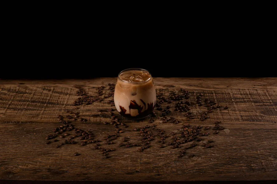 Glass of Iced Coffee on Brown Surface with Scattered Coffee Beans