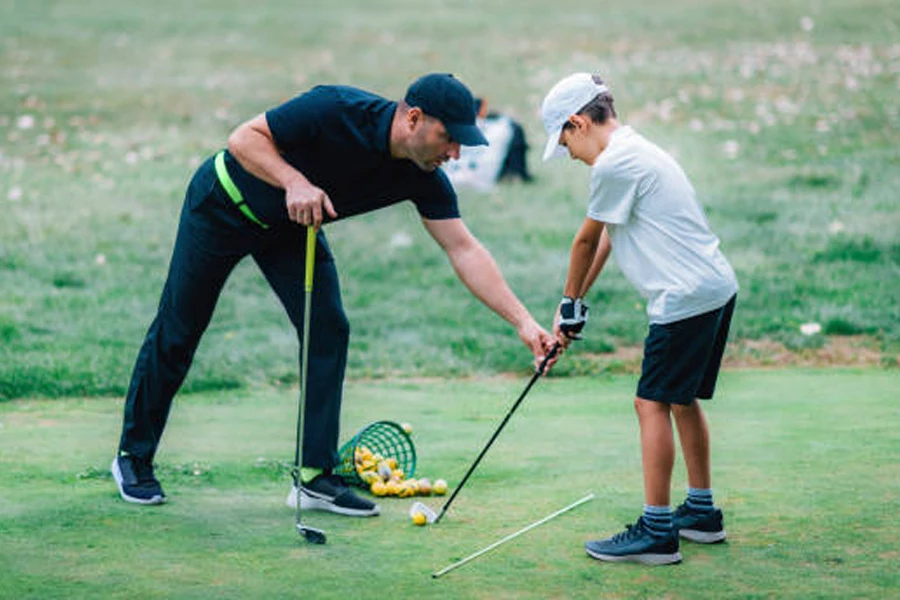 Golf coach teaching young player to swing on course