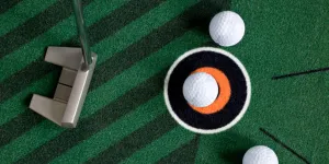 Golf putting mat with balls and putter sitting on top