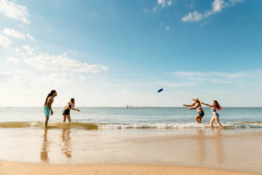 Group of four people throwing a frisbee on the beach