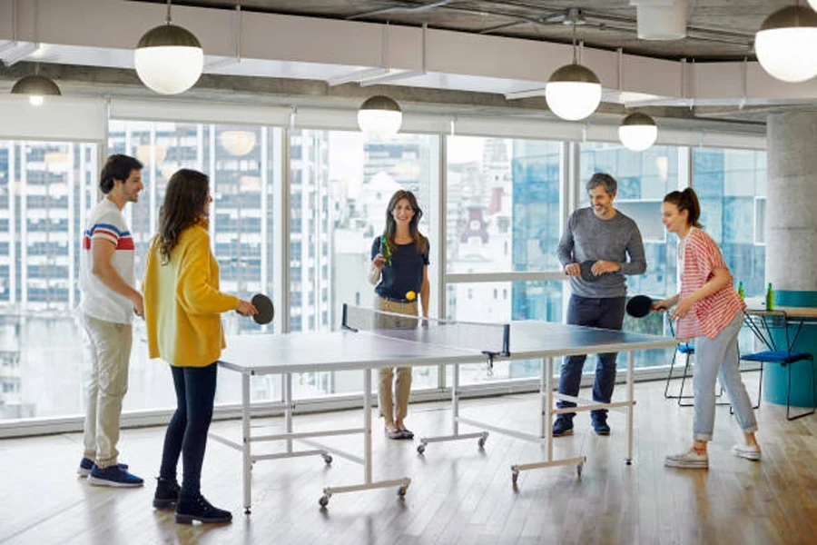 Group of friends playing table tennis in office space