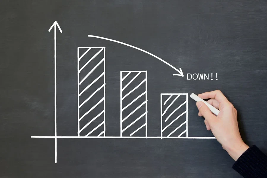 Hand drawing a downward graph on a blackboard